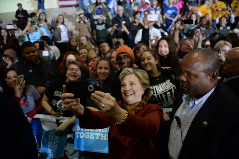 Democratic presidential nominee Hillary Clinton takes a selfie with supporters during a campaign event with her running mate Tim Kaine, October 22, 2016 at Taylor Allderdice High School in Pittsburgh, Pennsylvania. / AFP / Robyn BECK (Photo credit should read ROBYN BECK/AFP/Getty Images)